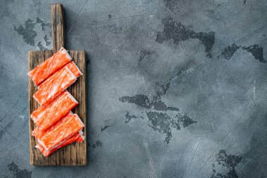 Asyalı abur cubur surimi seti, ahşap kesim tahtasında, gri arka planda, telif alanı ve metin alanı ile üst görünüm düz yatar