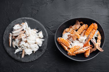 Pişmiş yengeç pençeleri ve bacakları. Siyah arka planda et seti. Üst manzara düz.