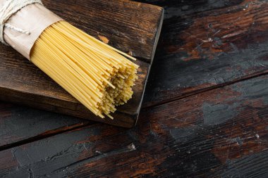 Kurutulmuş spagetti makarna, ahşap kesim tahtası üzerinde, eski siyah tahta masa zemininde, metin alanı ve yeri olan