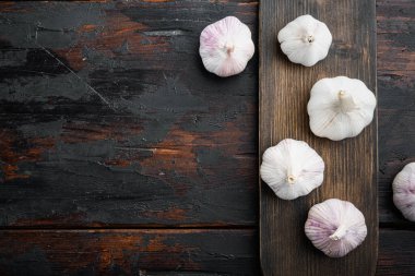 Organik çiftlik sarımsak seti, ahşap kesim tahtası, eski koyu ahşap masa arkaplanı, üst görünüm düz, kopyalanacak yer ve metin için yer