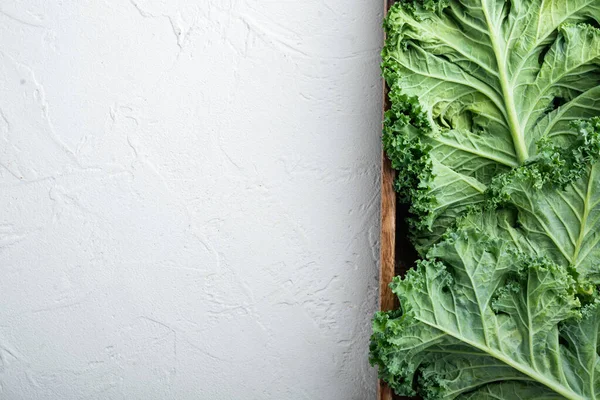 Fresh organic green kale leaves set, in wooden box, on white background, top view flat lay , with copyspace  and space for text