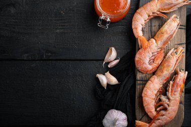 Çiğ karides, sarımsak, kireç, mango sosu ve ızgara seti için köri, ahşap kesim tahtası, siyah ahşap masa arkaplanı, üst görünüm düz, kopyalanmış yer ve metin için yer