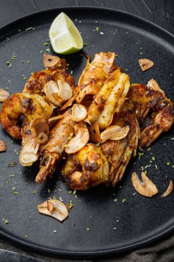 Kızarmış kaplan karidesi, mango turşusu ve çıtır sarımsak seti, tabakta, siyah arka planda.