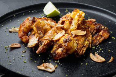 Yapışkan Mango Karidesleri ya da karidesler, tabakta, siyah arka planda