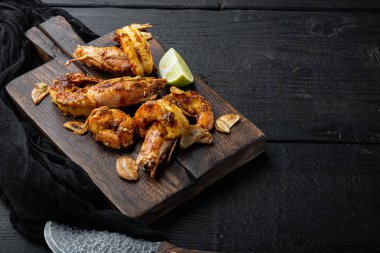 Büyük ızgara mango soslu karides ve köri seti, ahşap tahtada, siyah ahşap masa zemininde, kopyalanacak yer ve metin için yer var.