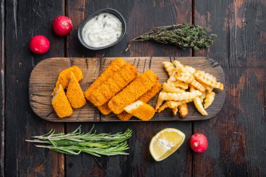 Balık kroket ve patates kızartması, tartar soslu İngiliz fast food seti, ahşap kesim tahtasının üzerinde, eski siyah tahta masa zemininde, üst düz manzaralı