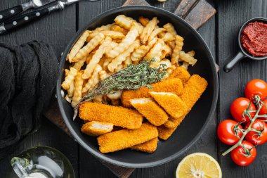 Sebzeli balık çubukları, kızgın demir tavada, siyah ahşap masa zemininde, üst manzara düz