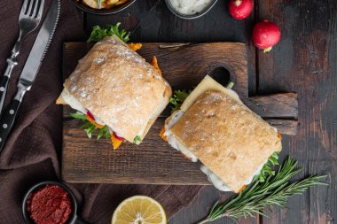 Taze yapılmış Balık Çubuklu Sandviç seti, ahşap kesim tahtasının üzerinde, eski siyah ahşap masa arka planında, üst düz manzaralı