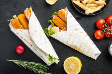 Balık kroketli, peynirli ve sebzeli tortilla rulosu, siyah arka planda, düz manzaralı.