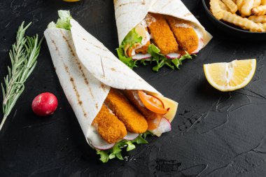 Balık kroketli, peynirli ve sebzeli tortilla rulosu, siyah zemin üzerinde, metin için telif alanı ve boşluk ile
