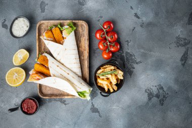 Balık kroketli tortilla rulosu, peynir ve sebze seti, ahşap tepside, gri arka planda, üst manzara düz, kopyalanacak yer ve metin için yer
