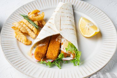 Balık kroketli, peynirli ve sebzeli sandviç. Tabakta, beyaz arka planda.