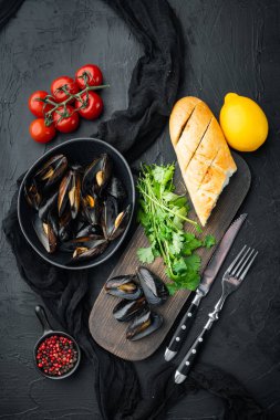 Maydanozlu ve baharatlı haşlanmış midyeler ve ekmek seti, kasede, siyah arka planda, üst manzara düz.