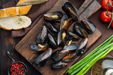 Çiğ midyeler, limon ve baget seti, ahşap kesim tahtası, eski siyah ahşap masa arka planı, üst düz manzara