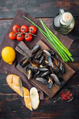 Midyeler beyaz şarap ve otlar içinde, ahşap kesme tahtasının üzerinde, eski siyah tahta masa arkasında, üst manzara düz yatıyordu.