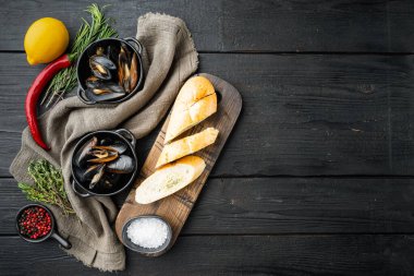 Baharat ve otla kaynamış midyeler, siyah ahşap masa arkaplanı, üst görünüm düz, kopyalanacak yer ve metin için boşluk