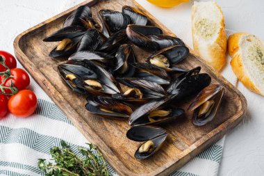 Beyaz şarap ve otlar içinde midye yahnisi, ahşap tepside, beyaz arka planda