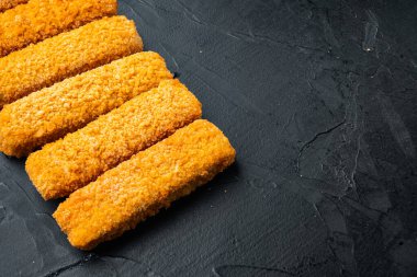 Donmuş balık parmakları, siyah arkaplanda, metin için telif alanı ve boşluk ile ayarlandı