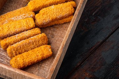 Donmuş balık parmakları, ahşap kutuda, eski koyu ahşap masa zemininde, kopyalanmış boşluk ve metin için