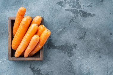 Taze ve tatlı havuç demeti seti, ahşap kutuda, gri arka planda, telif alanı ve metin için yeri olan üst görünüm düz yerde.