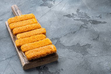 Donmuş balık çubukları. Organik balık yemi seti, ahşap kesim tahtasında, gri arka planda, metin için telif alanı ve boşluk ile