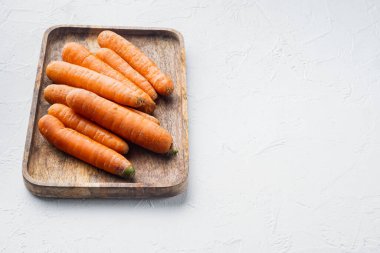 Renkli turuncu havuç demetleri, ahşap tepside, beyaz arka planda, metin alanı ve boşluğu olan