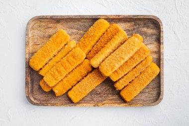 Donmuş balık çubukları. Organik balık yemi seti, ahşap tepside, beyaz arka planda, üst manzara düz yerde.