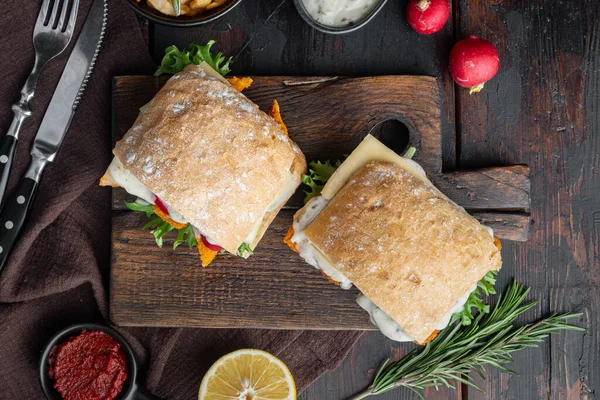 Taze yapılmış Balık Çubuklu Sandviç seti, ahşap kesim tahtasının üzerinde, eski siyah ahşap masa arka planında, üst düz manzaralı