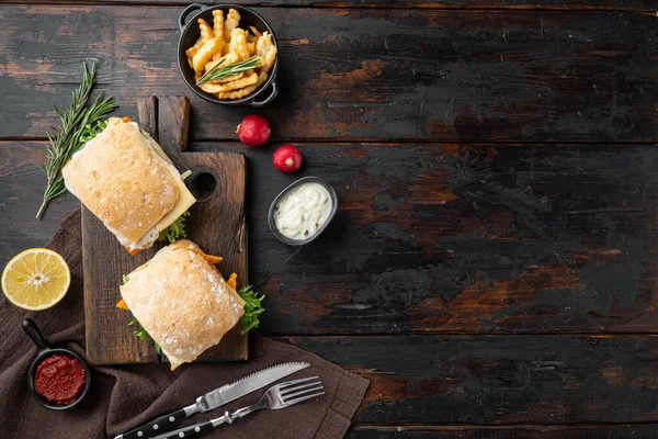 Taze yapılmış Balık Çubuklu Sandviç seti, ahşap kesim tahtası, eski koyu ahşap masa arkaplanı, üst görünüm düz, metin alanı ve yeri ile metin alanı