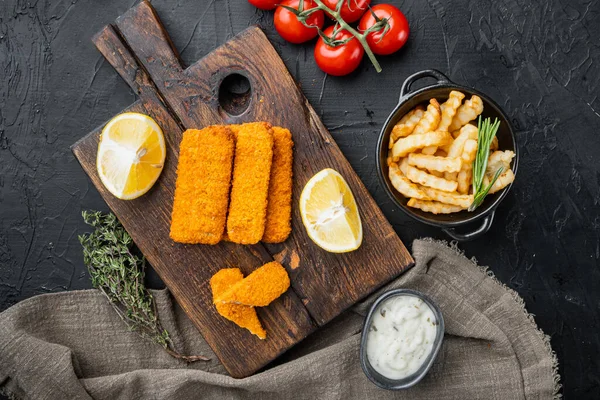 Fish Sticks with vegetables set, on wooden cutting board, on black background, top view flat lay