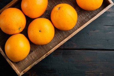 Çiğ Organik Cara Göbek Portakalları seti, ahşap kutuda, eski koyu ahşap masa zemininde, üst görünüm düz yerde, metin için telif alanı ve boşluk ile