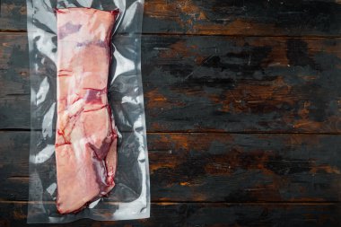 Vakum paketlemedeki sığır kaburgaları, market seti, eski koyu ahşap masa arkaplanı, üst görünüm düz yatağı, metin için metin alanı ve boşluğu