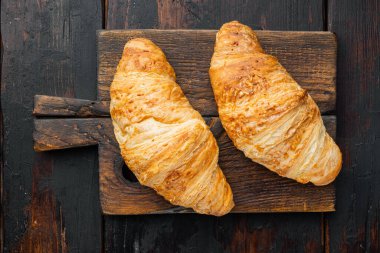 Eski siyah ahşap masa arka planında taze kruvasan seti.