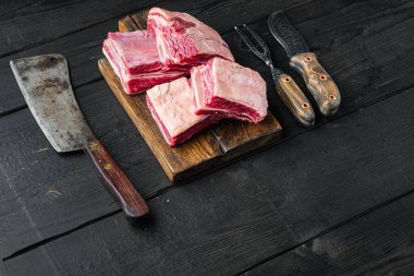 Çiğ pirzola seti, ve eski kasap satır bıçağı, siyah ahşap masa arka planı, metin için kopyalama alanı ile