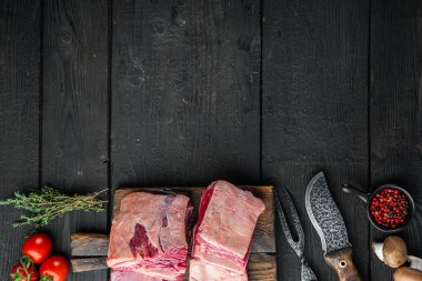 Çiğ et kaburga seti, malzemeleri ile, ve eski kasap satır bıçağı, siyah ahşap masa arka planı, üst görünüm düz, metin için kopyalama alanı ile