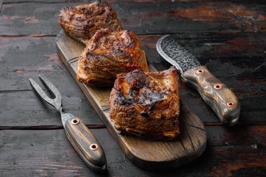 Lezzetli, zengin bir sos seti içinde, eski, siyah ahşap masa arka planında pişmiş pirzola.