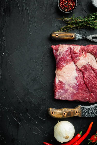Raw brisket beef cut. Black Angus beef set,with ingredients for smoking  making  barbecue, pastrami, cure, on black stone background, top view flat lay,  with copy space for text