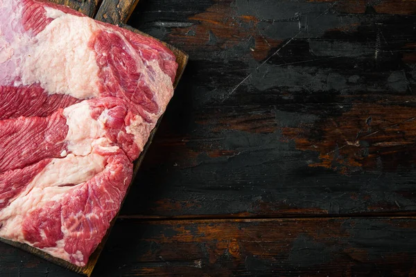 Eski koyu ahşap masa arkaplanı üzerine, bütün bir parça çiğ et seti, üst görünüm düz, metin alanı için kopyalama alanı ile