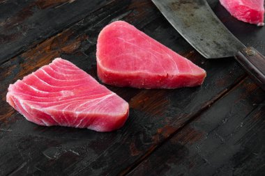 Çiğ organik ton balığı filetosu. Deniz ürünleri seti, ve eski kasap satırı bıçağı, eski siyah ahşap masa arka planında