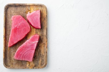 Çiğ ton balığı parçaları, ahşap tepside, beyaz taş zemin üzerinde, telif alanı ve metin için yeri olan üst görünüm düz yerde.