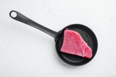 Çiğ ton balığı bifteği, taze kırmızı ton balığı fileto seti, kızarmış demir tavada, beyaz taş arka planda, düz manzaralı