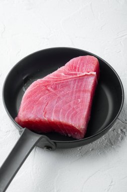 Çiğ organik ton balığı filetosu. Deniz ürünleri seti, kızgın demir tavada, beyaz taş arka planda.