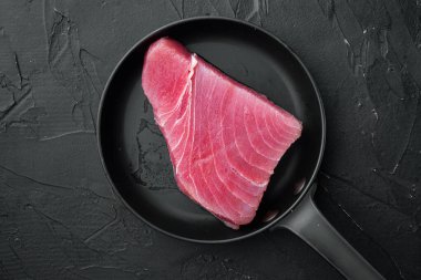 Çiğ ton balığı bifteği, taze kırmızı ton balığı fileto seti, kızgın demir tavada, siyah taş zemin üzerinde, telif alanı ve metin için yeri olan üst görünüm düz yerde.
