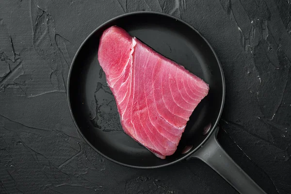 Çiğ ton balığı bifteği, taze kırmızı ton balığı fileto seti, kızgın demir tavada, siyah taş zemin üzerinde, telif alanı ve metin için yeri olan üst görünüm düz yerde.