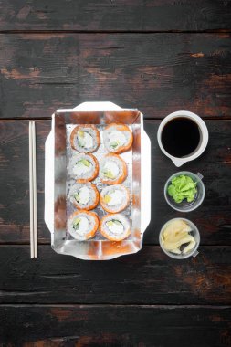 Farklı suşi çeşitleri ve rulo fro, somon ve ton balığı teslimat konsepti seti, eski koyu ahşap masa arka planı, üst görünüm düz, metin için yer ve mekan