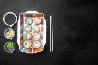 Suşi rulo dağıtım seti, siyah taş zemin üzerinde, üst görünüm düz, metin için telif alanı ve boşluk ile yatar