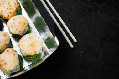 Lezzetli suşi tek kullanımlık kutularda yuvarlanıyor, siyah taş zemin üzerinde, üst görünüm düz yerde, metin için metin alanı ve boşluğu ile.