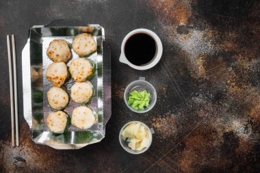 Suşi, eski koyu rustik arka planda, metin için metin alanı ve boşluğu olan, üst görünüm düz yatağında, paket kutusu setinde yuvarlanır.