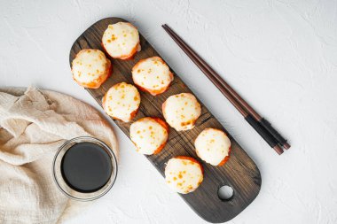 Japon suşi rulolarının adı wasabi ve somon balığı setiyle fırınlanmış Ebi, beyaz taş zemin üzerinde, telif alanı ve metin için yeri olan düz manzaralı.