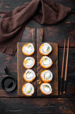 Suşi rulo geyşa ateşte kavrulmuş somon, levrek, karides, avokado seti, eski siyah ahşap masa arkaplan, üst düz yatıyordu